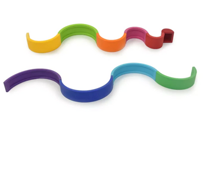 Arco-íris feito de tiras de silicone nas cores vinho, vermelho, rosa, laranja, amarelo, verde limão, verde, azul claro, azul escuro, roxo. Peças desmontáveis para brincar e empilhar e encaixar. Peças colocadas em outro formato para ilustrar ourtos modos de brincar.