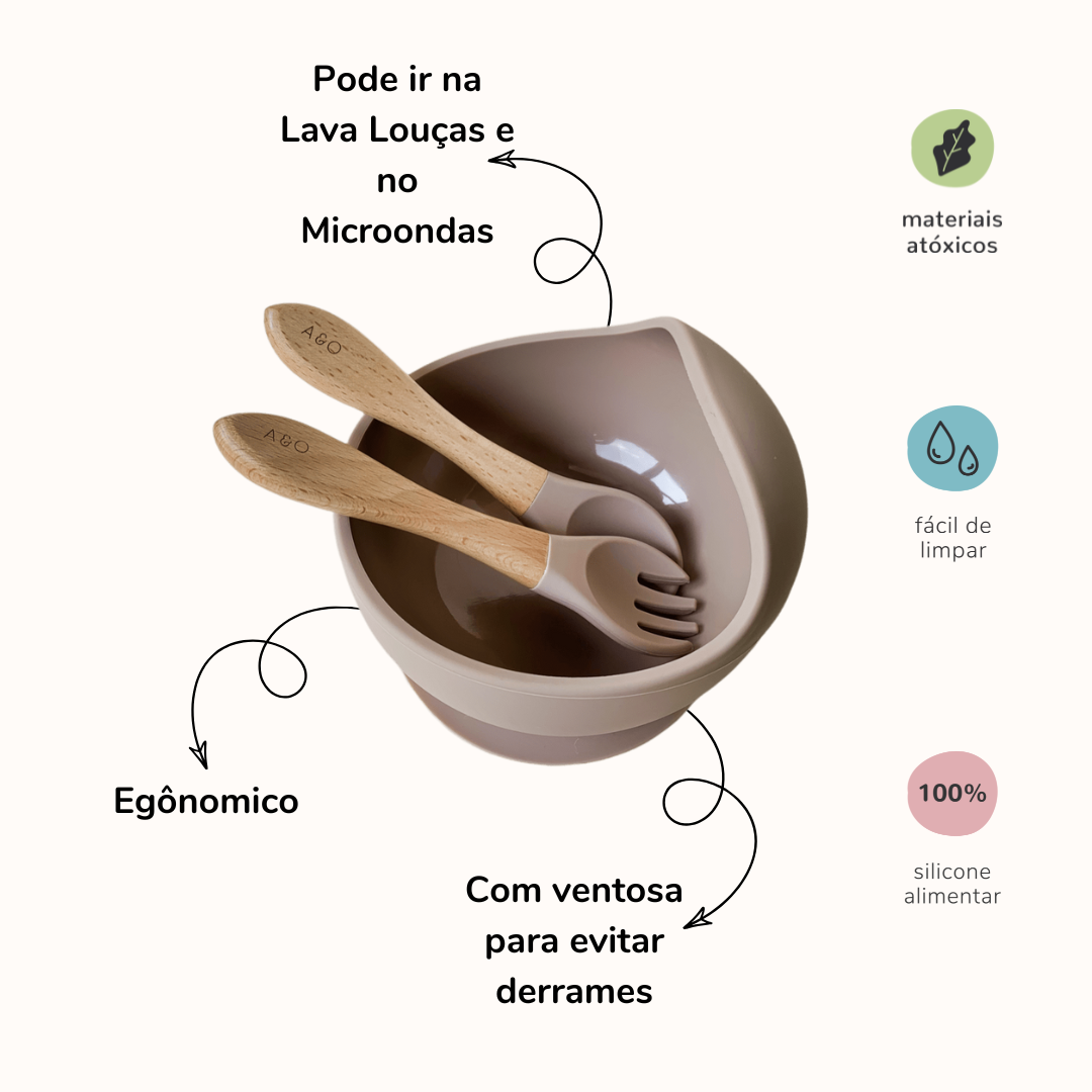 Um bowl com uma colher e um garfo com cabo de madeira e ponteira de silicone na cor nude. A imagem contem informações sobre o produto.